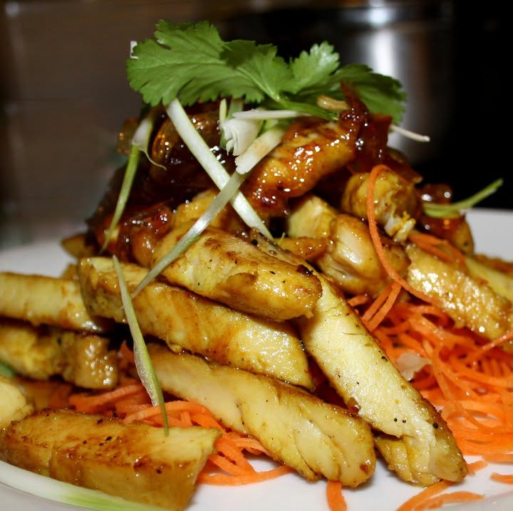 Glazed chicken strips on shredded carrot topped with coriander